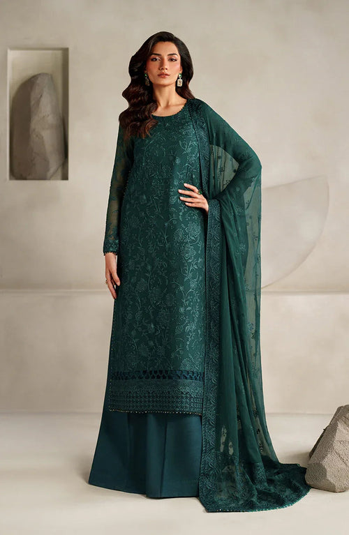 Woman wearing a teal embroidered outfit with a matching dupatta against a neutral background