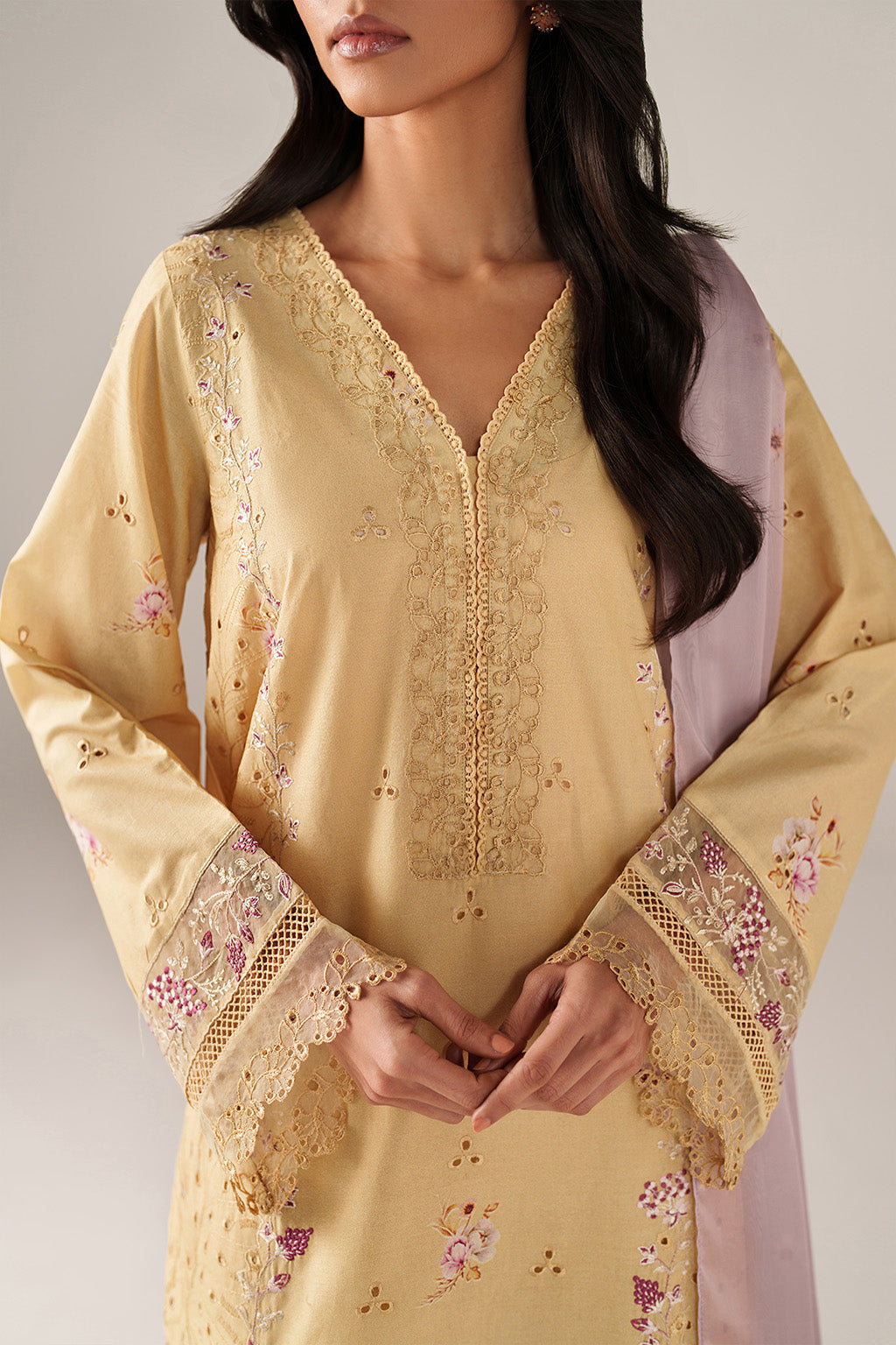 Woman wearing a yellow embroidered kurta with a plain background