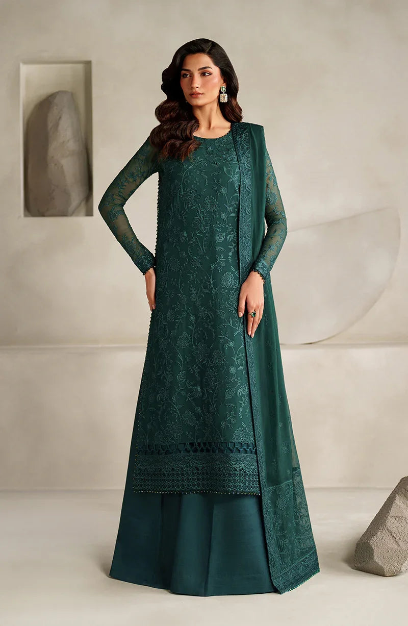 Woman wearing a teal embroidered traditional outfit against a neutral background