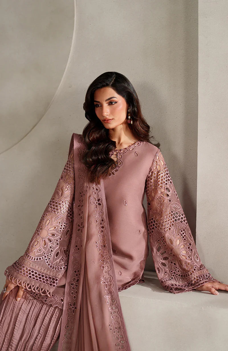 Woman wearing a pink traditional outfit with intricate designs against a neutral background