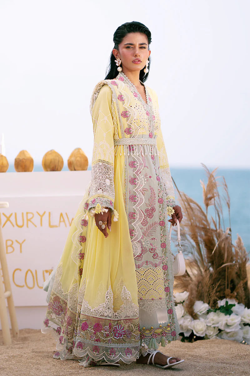 Woman in a yellow and white embroidered outfit standing in front of decorative elements.