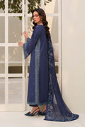 Woman wearing a blue traditional outfit with a matching dupatta in front of a white door.