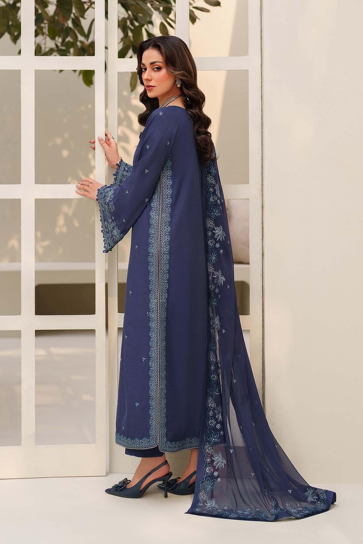 Woman wearing a blue traditional outfit with a matching dupatta in front of a white door.