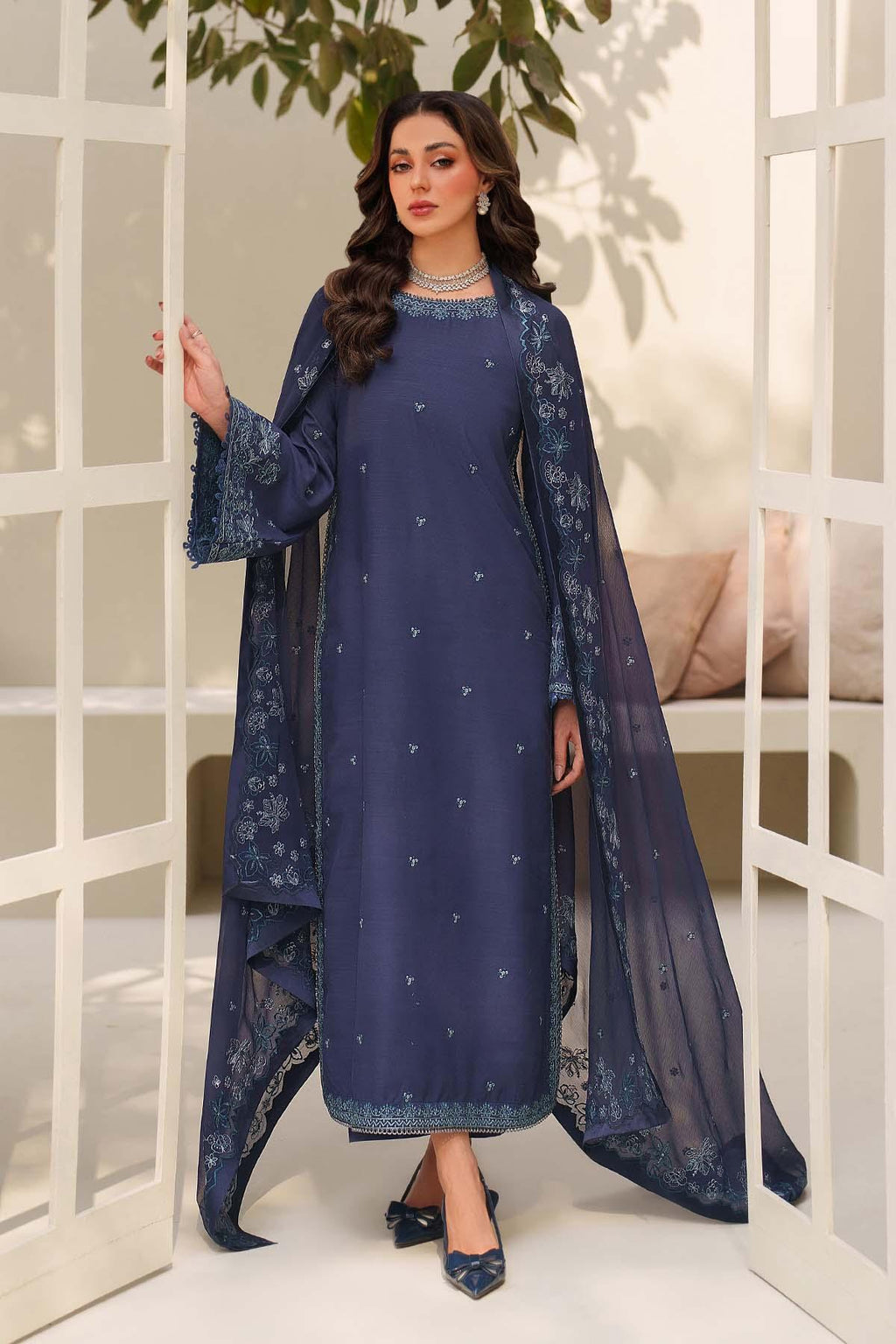 Woman wearing a navy blue traditional outfit with floral patterns indoors.