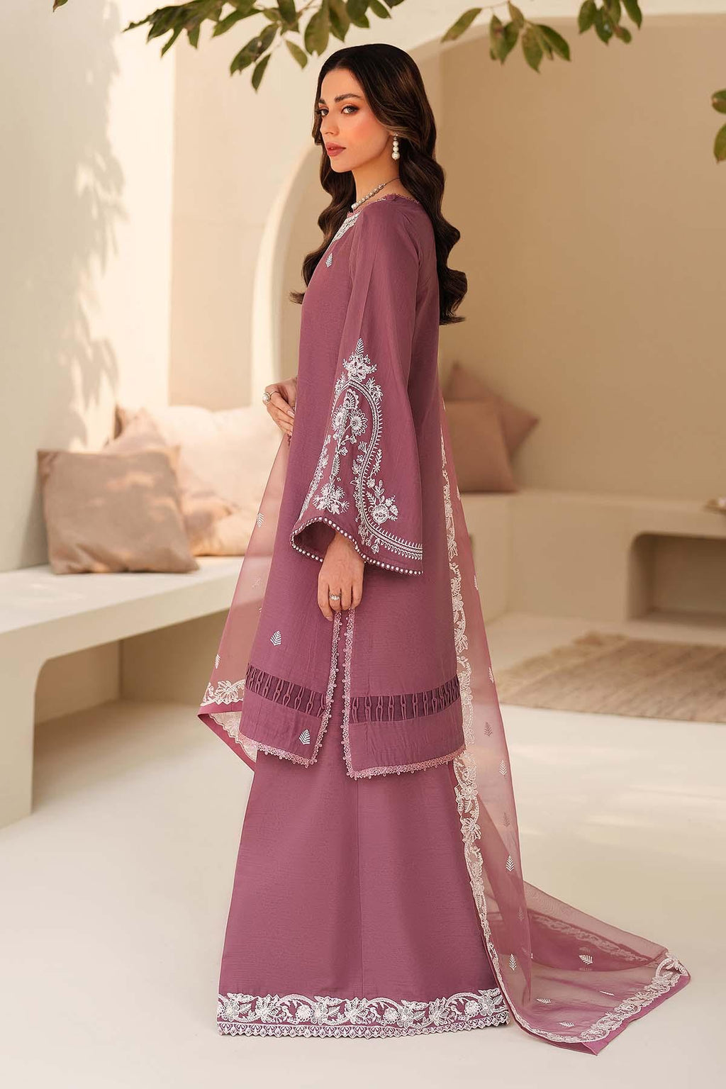 Woman in a purple traditional outfit with white embroidery in a minimalistic setting
