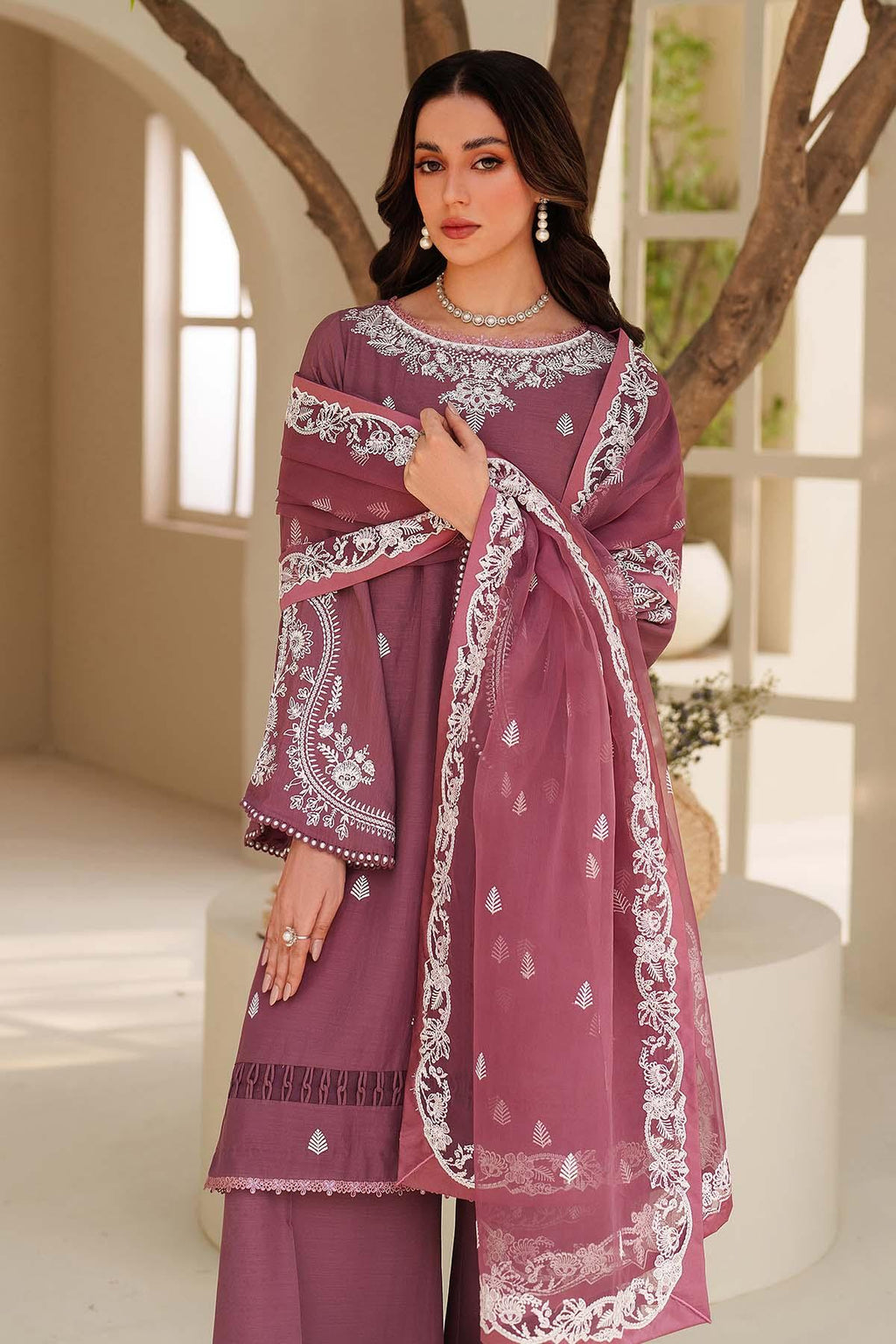 Woman wearing a purple embroidered outfit with a white background