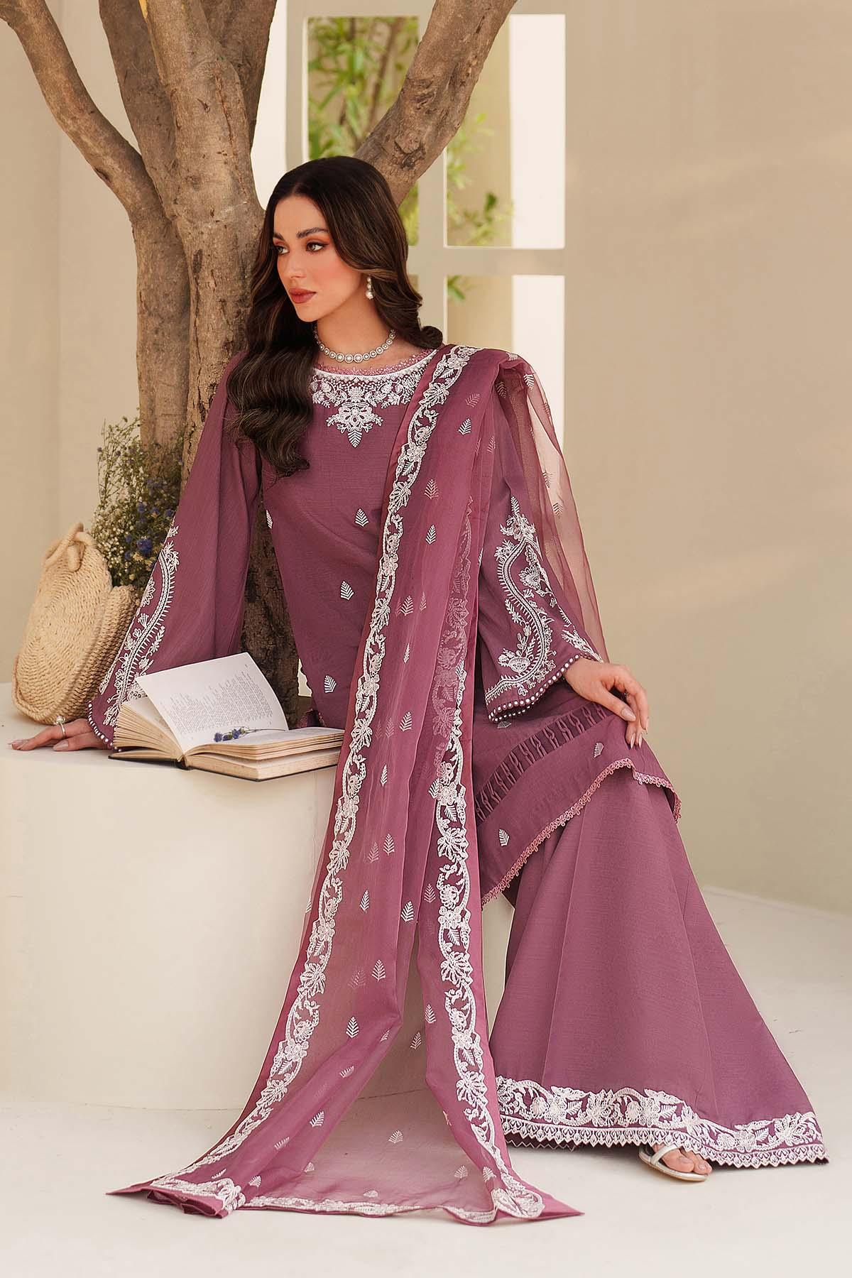 Woman in a purple traditional outfit with white embroidery, sitting on a white surface.