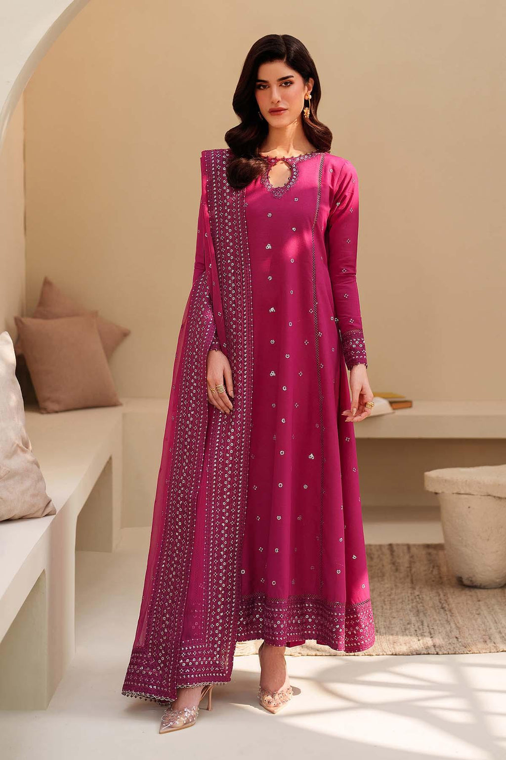 Woman wearing a pink traditional outfit with a matching dupatta in a well-lit room.