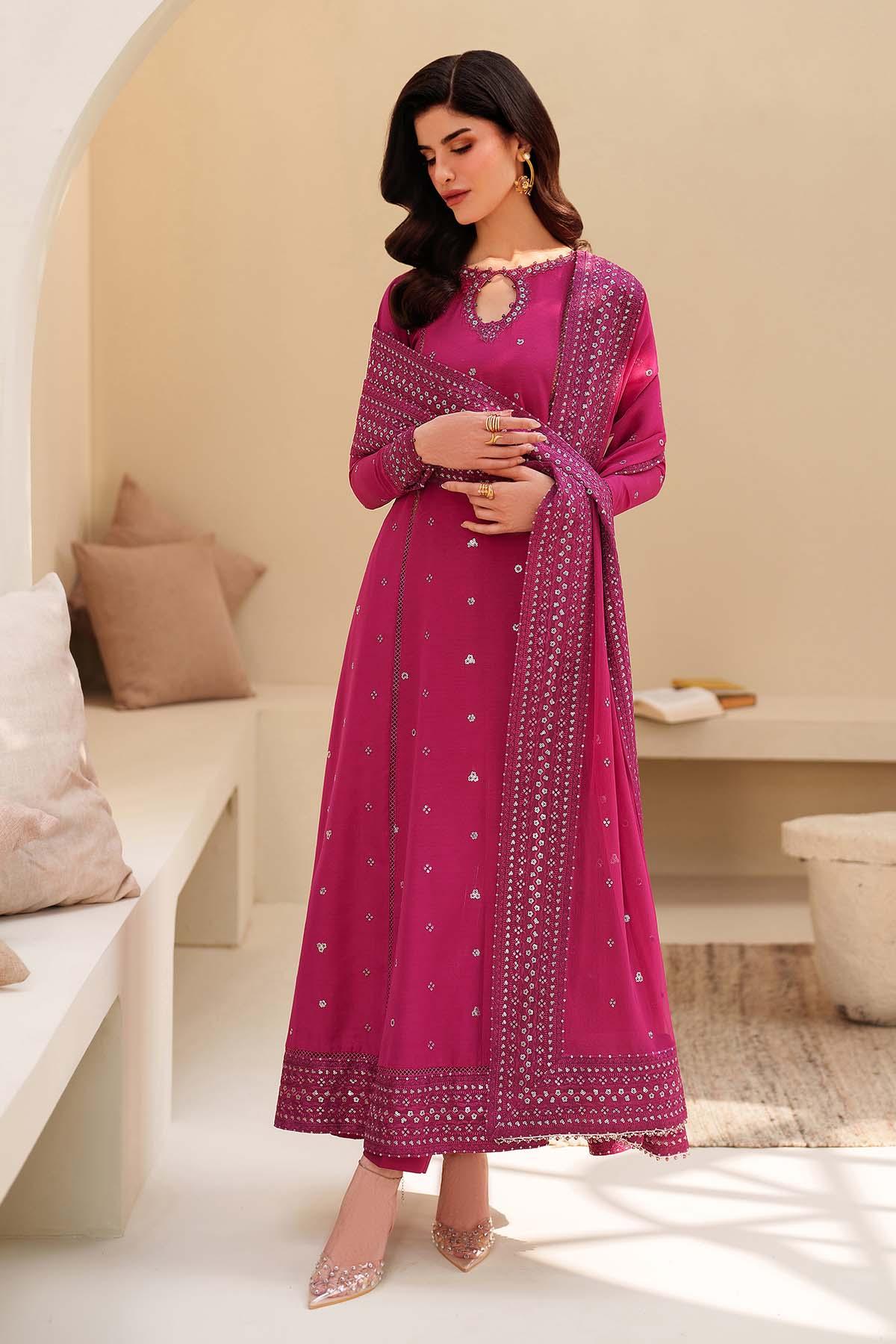 Woman wearing a pink traditional outfit with a matching dupatta in a minimalistic room.