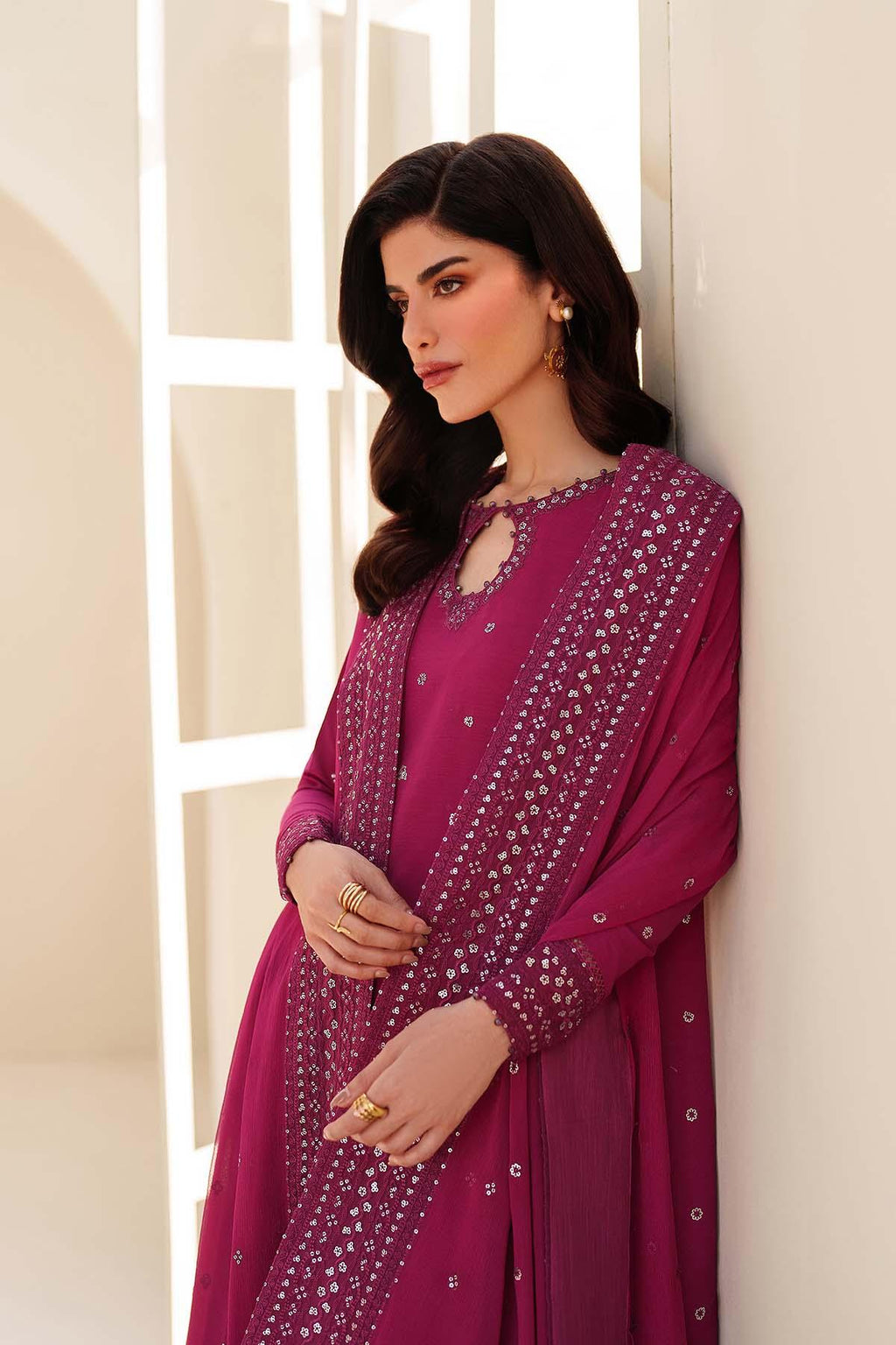 Woman wearing a magenta traditional outfit with intricate patterns against a neutral background