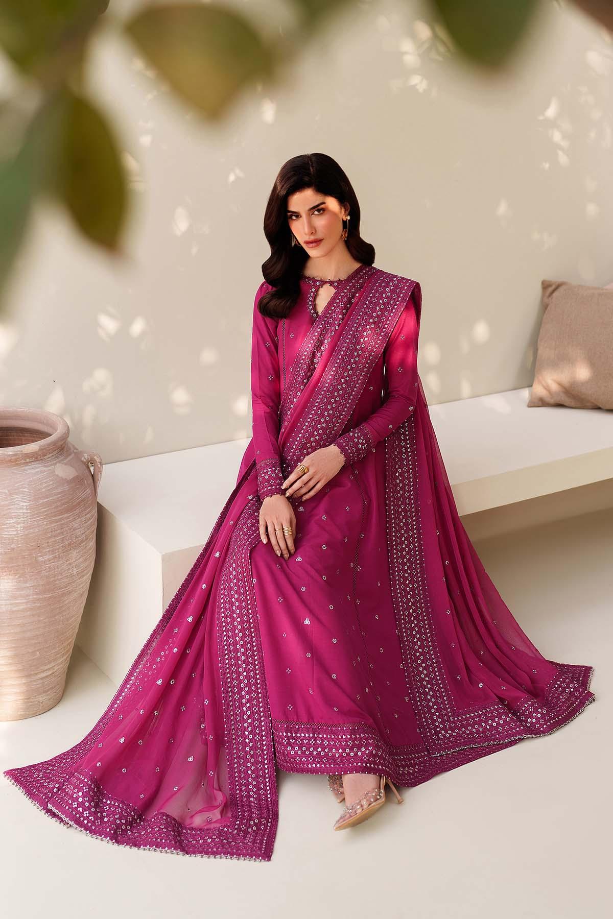 Woman in a pink saree sitting on a white couch with a neutral background