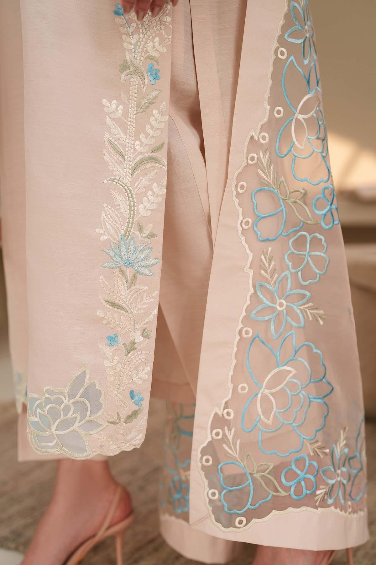 Light pink outfit with floral embroidery on a neutral background