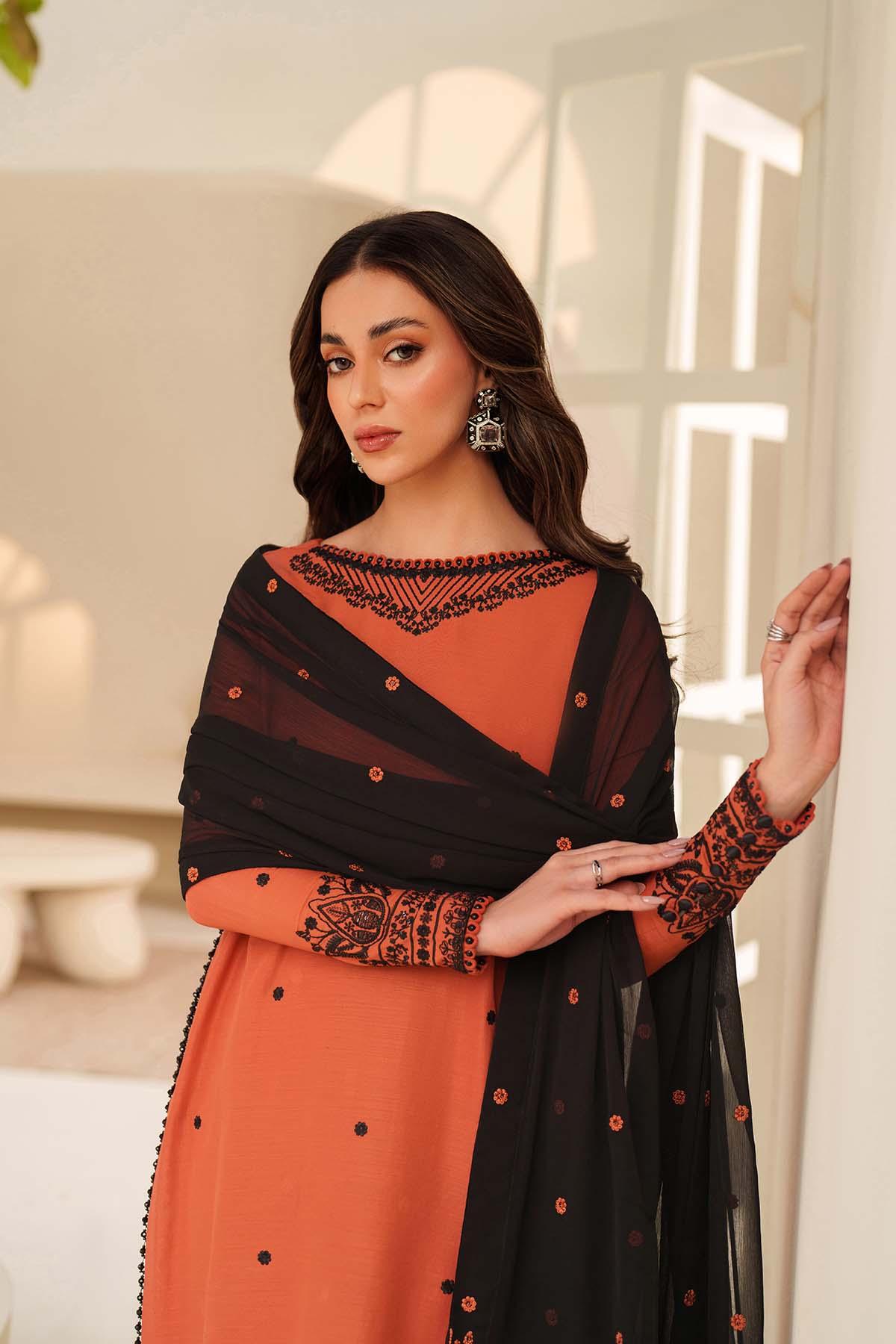 Woman wearing an orange and black traditional outfit with intricate designs.