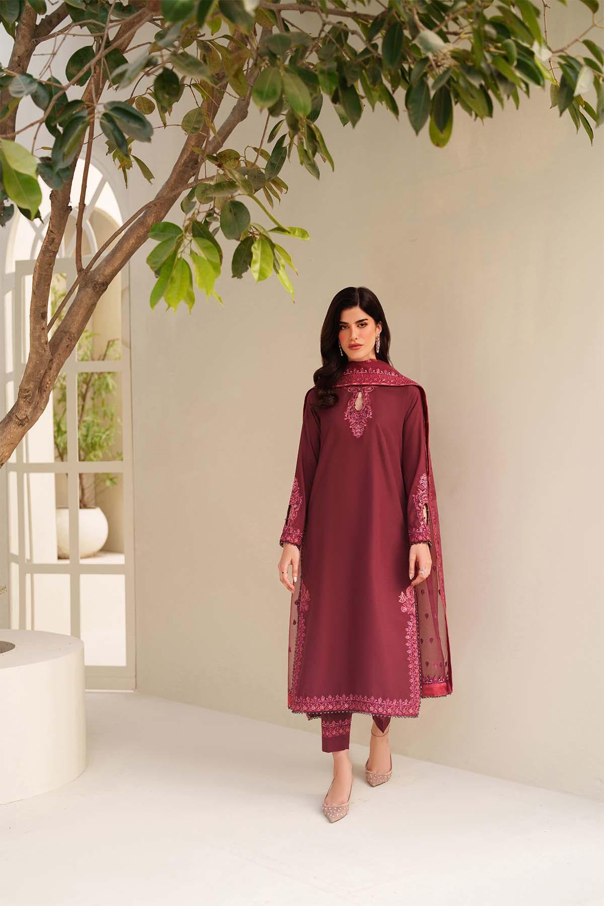 Woman in a maroon traditional outfit standing indoors with a neutral background