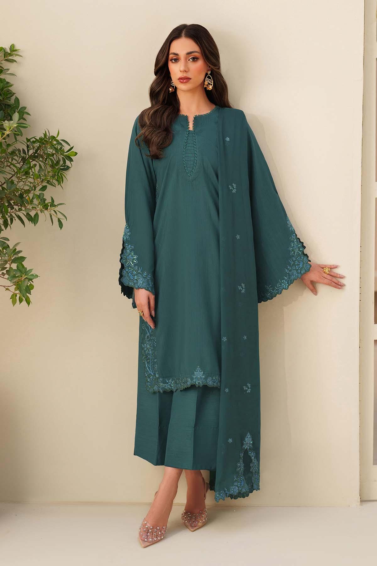 Woman wearing a teal dress with floral embroidery against a neutral background