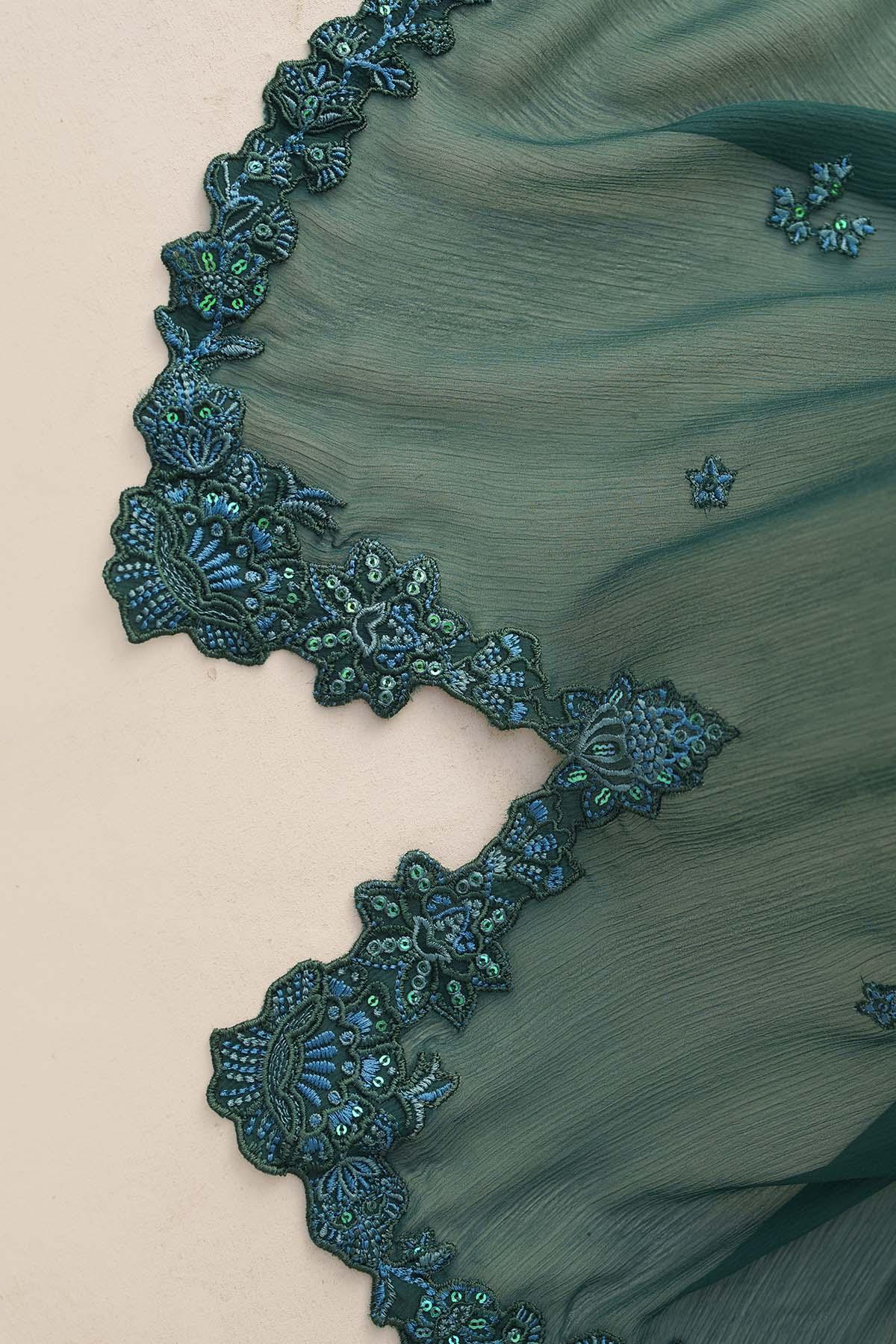Close-up of teal fabric with intricate lace detailing on a beige background