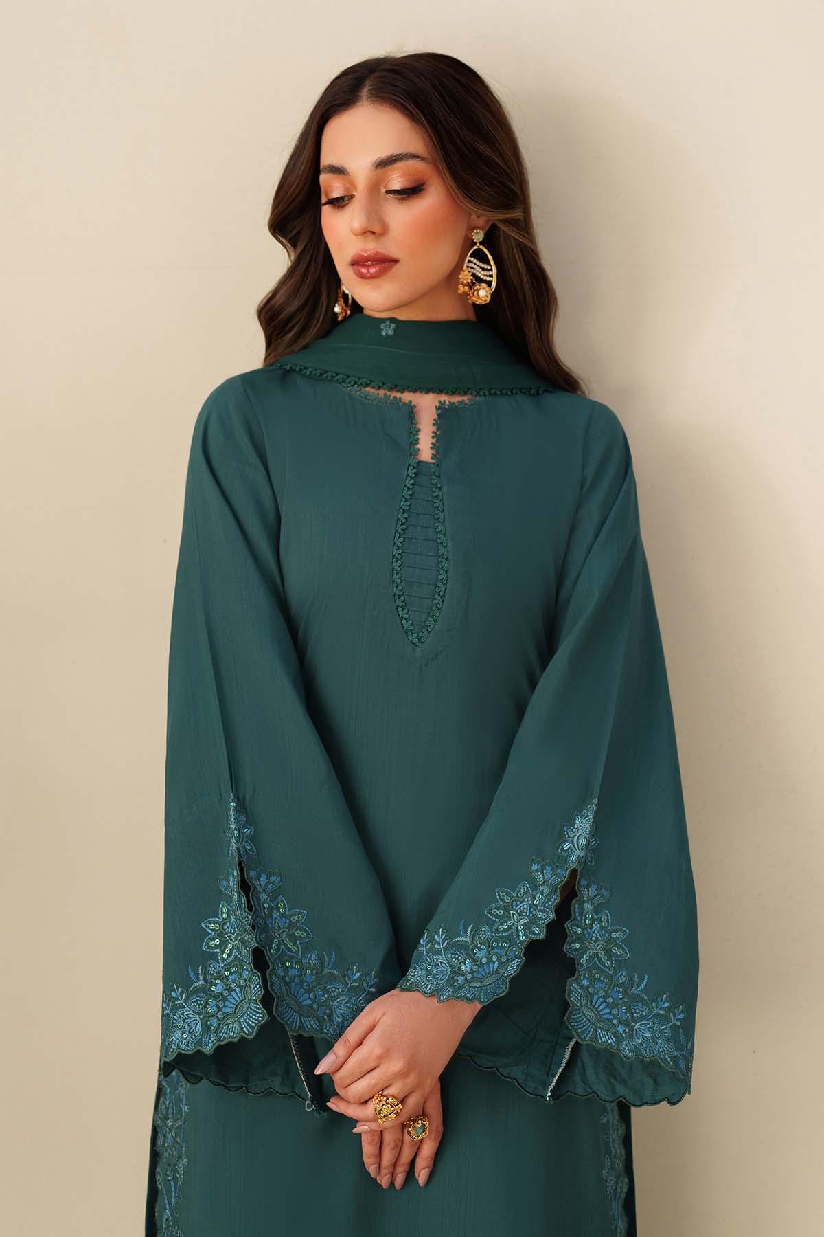 Woman wearing a teal dress with intricate lace details against a beige background