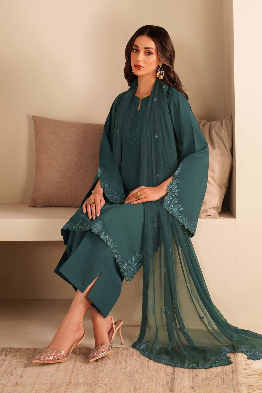 Woman wearing a teal traditional outfit with a sheer dupatta in a minimalistic setting.