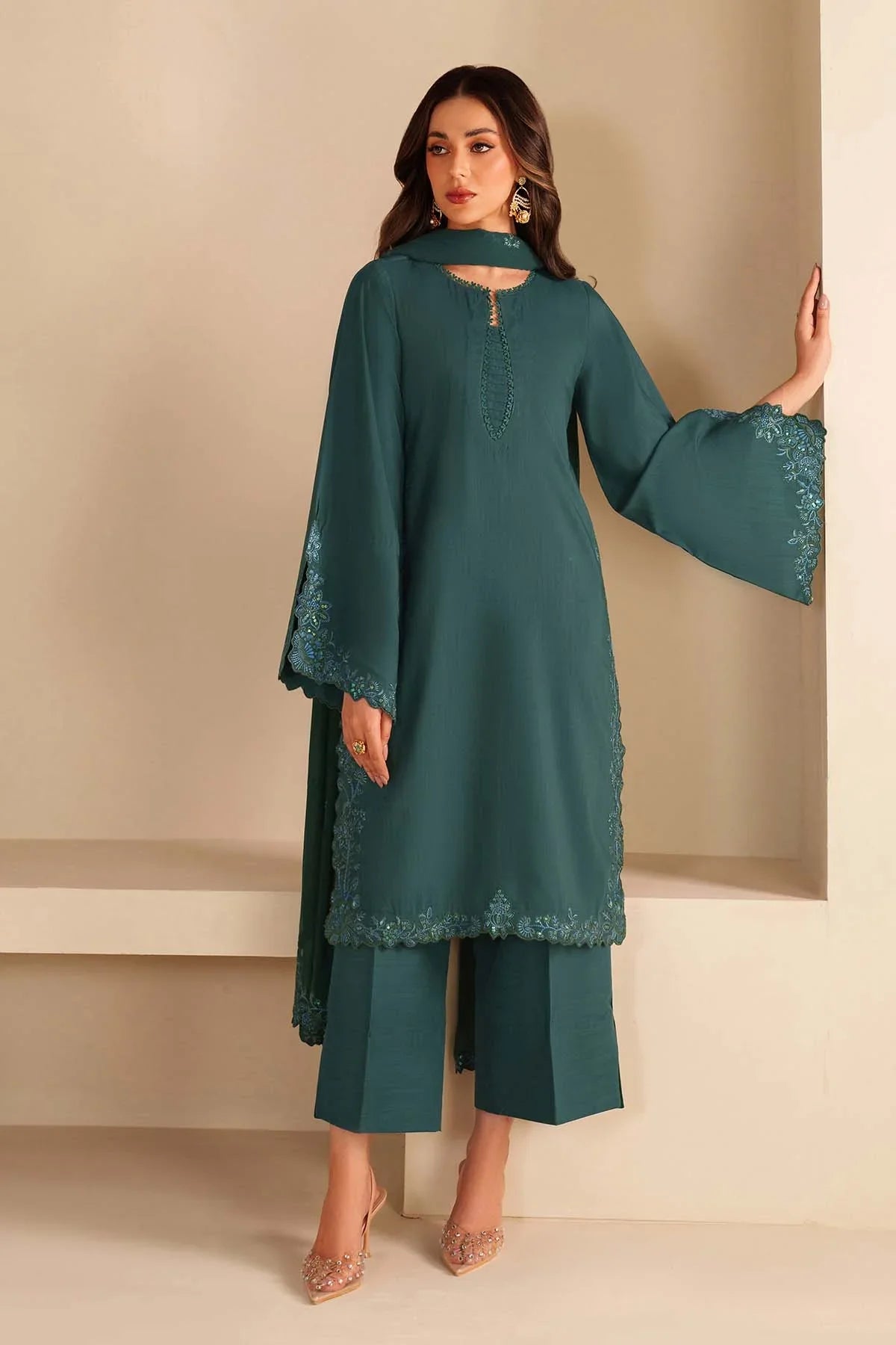 Woman wearing a teal outfit with lace details against a beige background