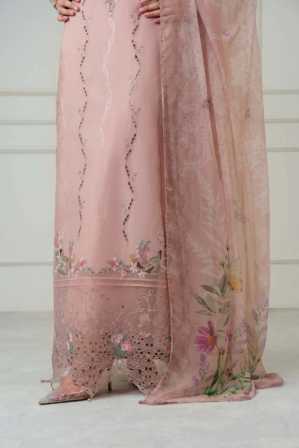 A close-up of a dusty pink traditional outfit with floral embroidery and a matching sheer dupatta draped over the floor.