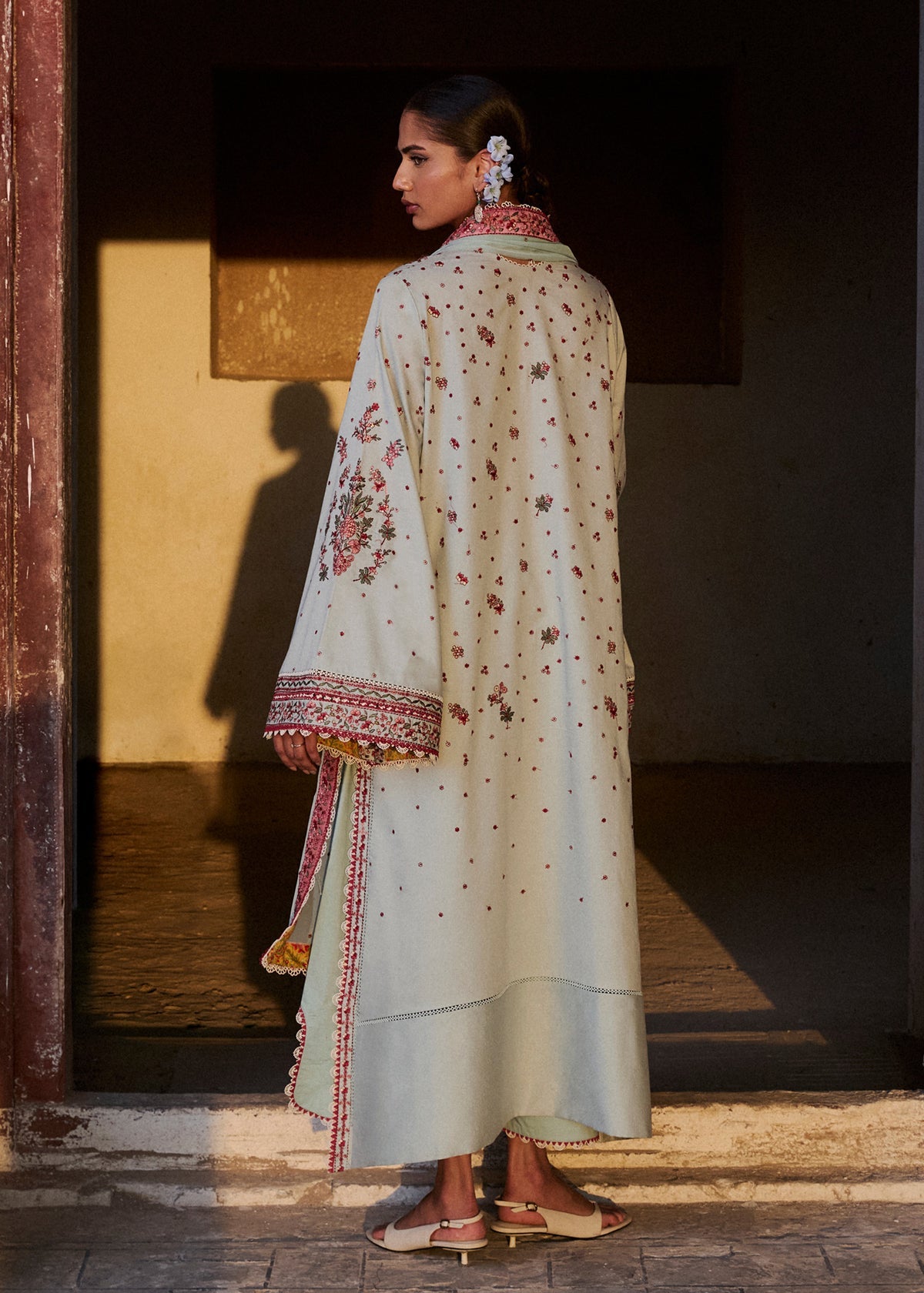 Woman in a traditional embroidered outfit standing in a dimly lit room.