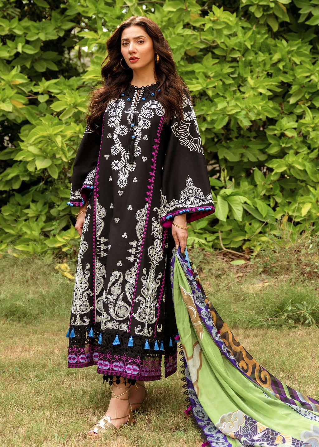 Woman wearing a black and white patterned dress with a green dupatta outdoors.