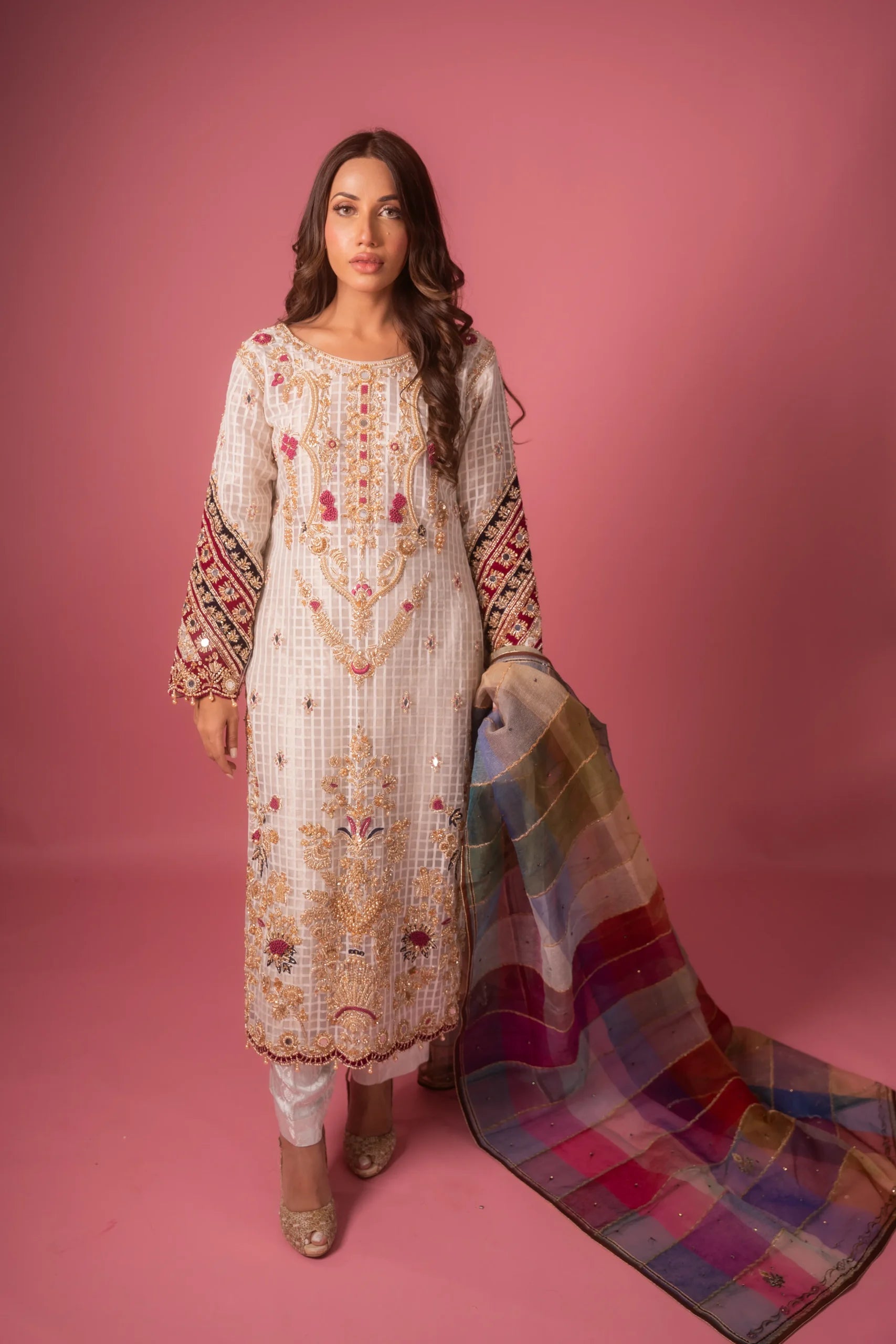 A woman wearing a traditional Colorful Jasmine dress with check organza fabric, featuring intricate embellishments and a dupatta with a vibrant plaid pattern.