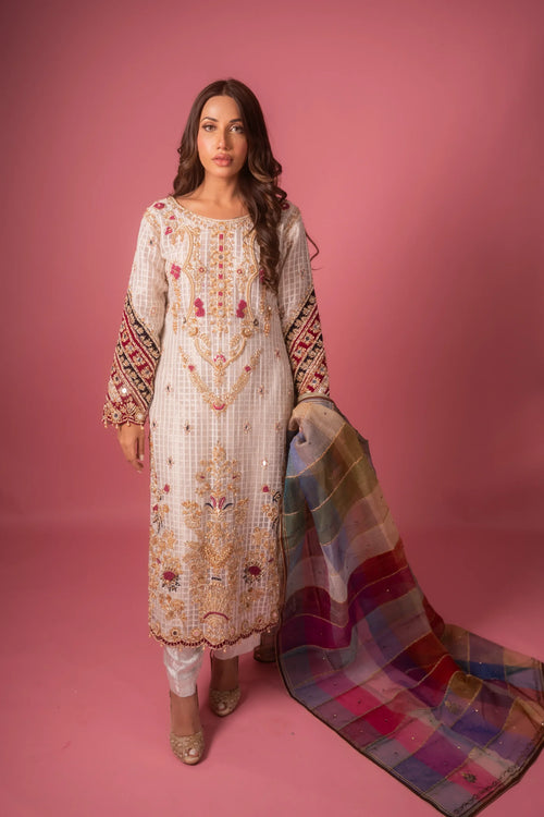 A woman wearing a traditional Colorful Jasmine dress with check organza fabric, featuring intricate embellishments and a dupatta with a vibrant plaid pattern.