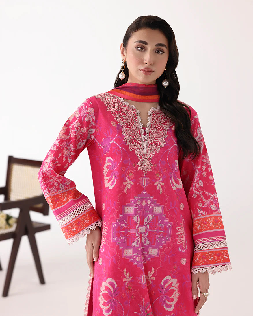 Woman wearing a bright pink embroidered dress with a white background