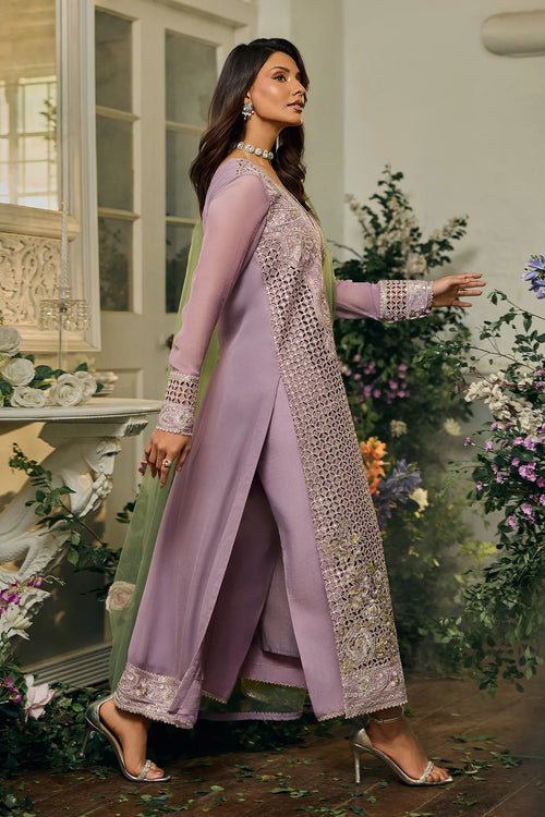 Woman in a lavender traditional outfit with floral decorations in the background