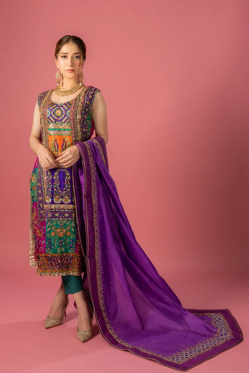 A woman posing in a vibrant purple and multicolor traditional dress with intricate embroidery and a dupatta.