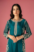 A woman wearing a traditional, dark sea green, embroidered dress with a floral design, paired with a dupatta and a shirt.