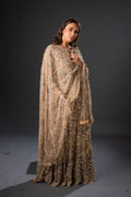 A woman wearing a traditional, embellished, golden maxi dress with a dupatta, featuring intricate front embroidery and a sweeping tail.