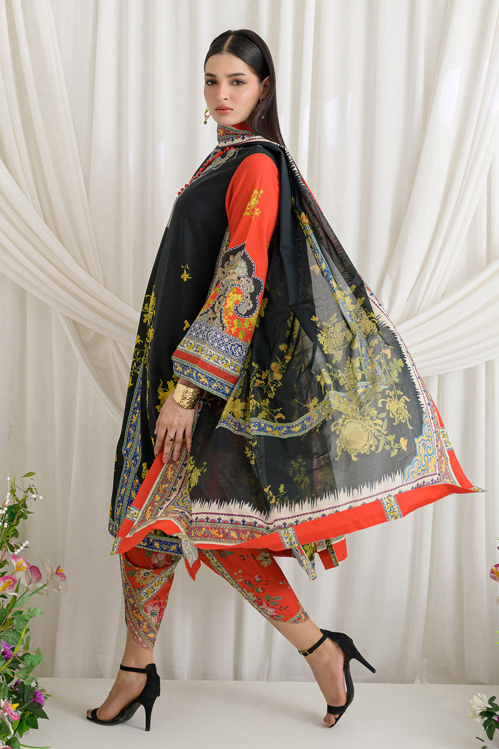 Woman wearing a traditional outfit with a black dupatta featuring colorful patterns on a white background