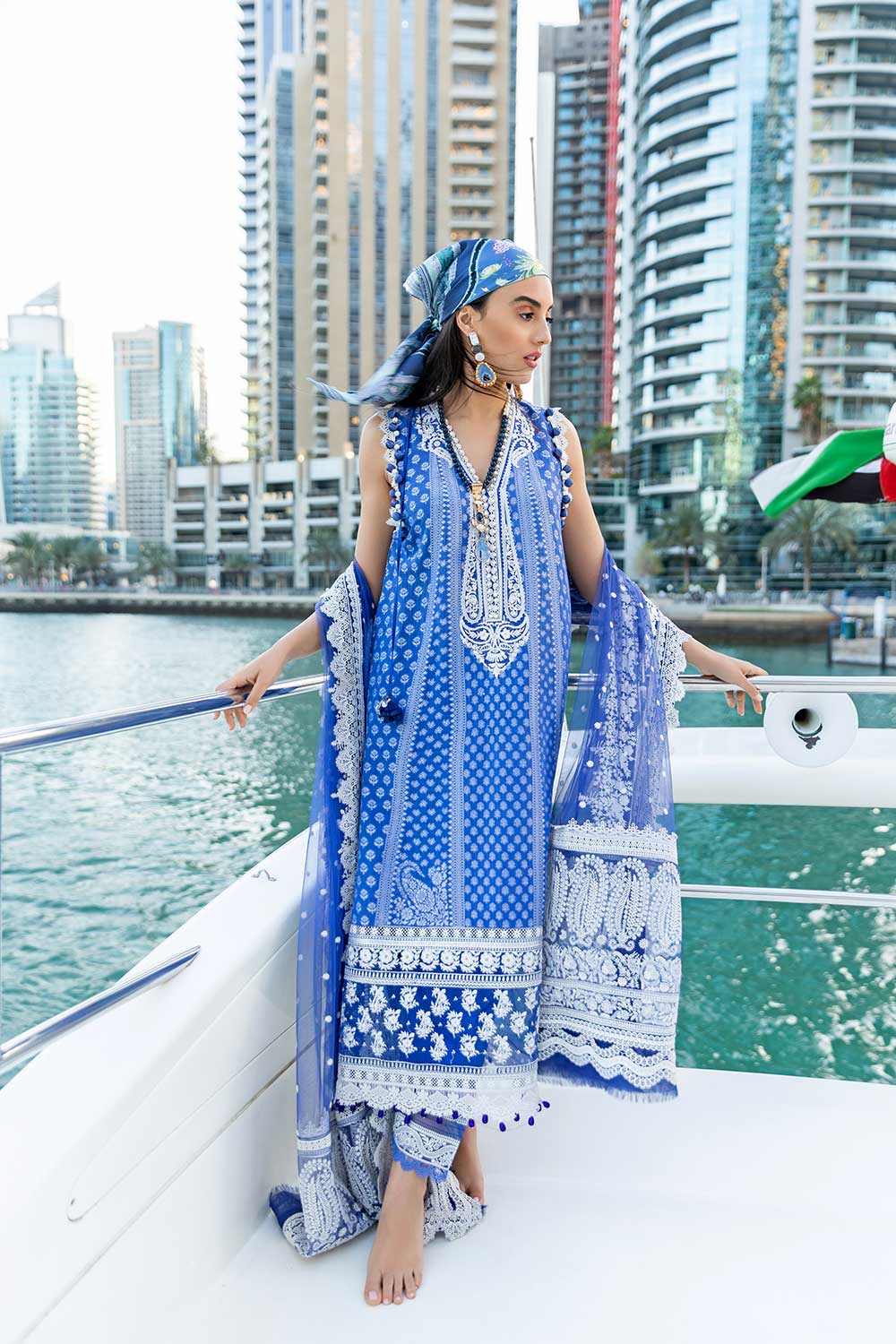 Woman in a blue and white traditional outfit on a boat with city skyline in the background