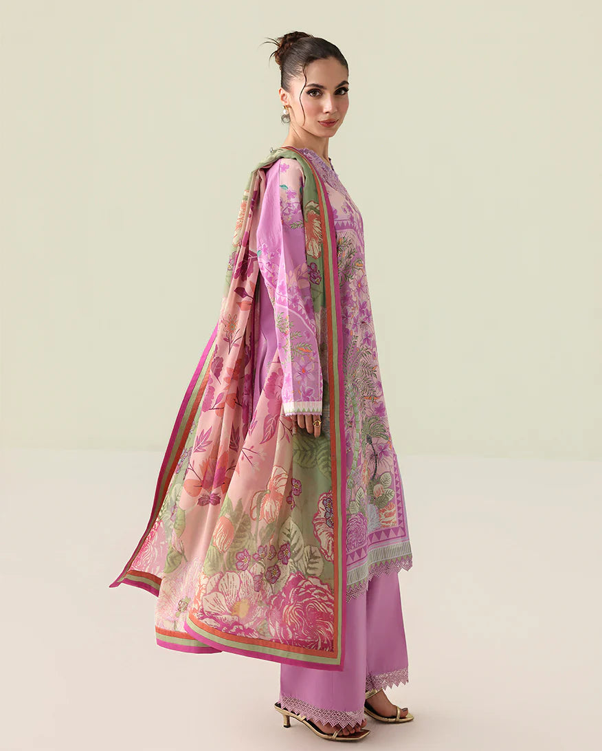 Woman wearing a pink and green embroidered traditional outfit on a light background