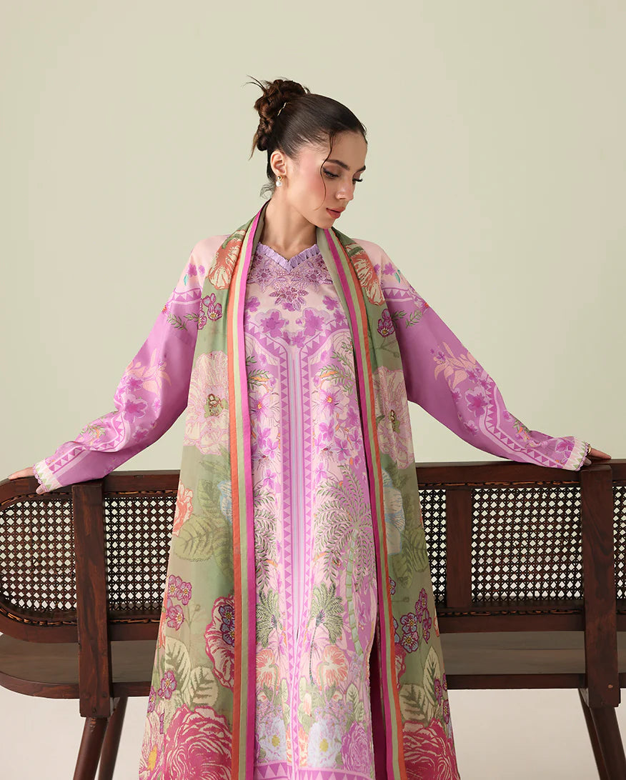 Woman wearing a floral pink and green dress with a matching shawl, sitting on a wooden chair.