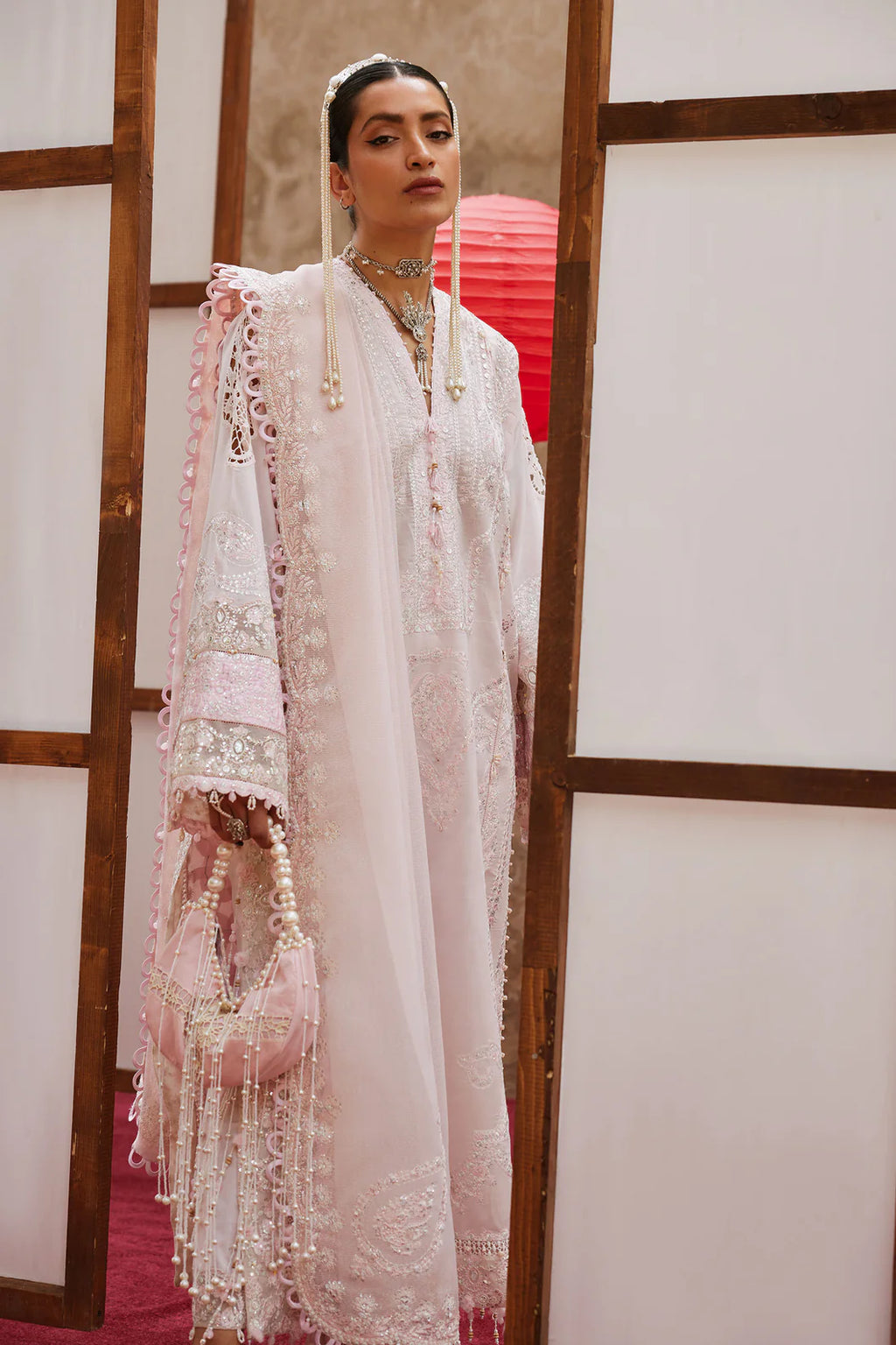 Woman in a traditional embroidered outfit with a red lantern in the background