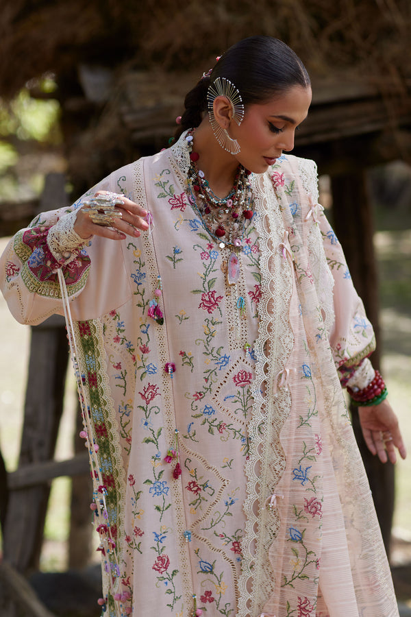 Woman wearing a traditional embroidered outfit with floral patterns.