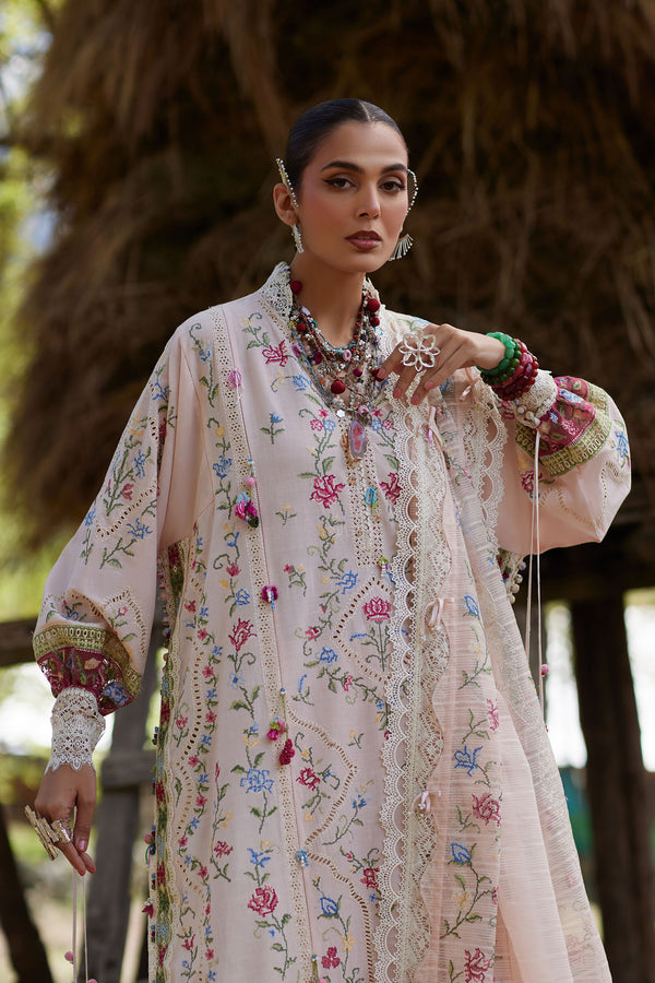 Woman in a floral embroidered outfit with jewelry, standing outdoors.