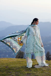 Woman in a light blue embroidered outfit holding a colorful scarf with mountains in the background