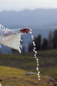 Person holding a string of flowers with a mountainous background