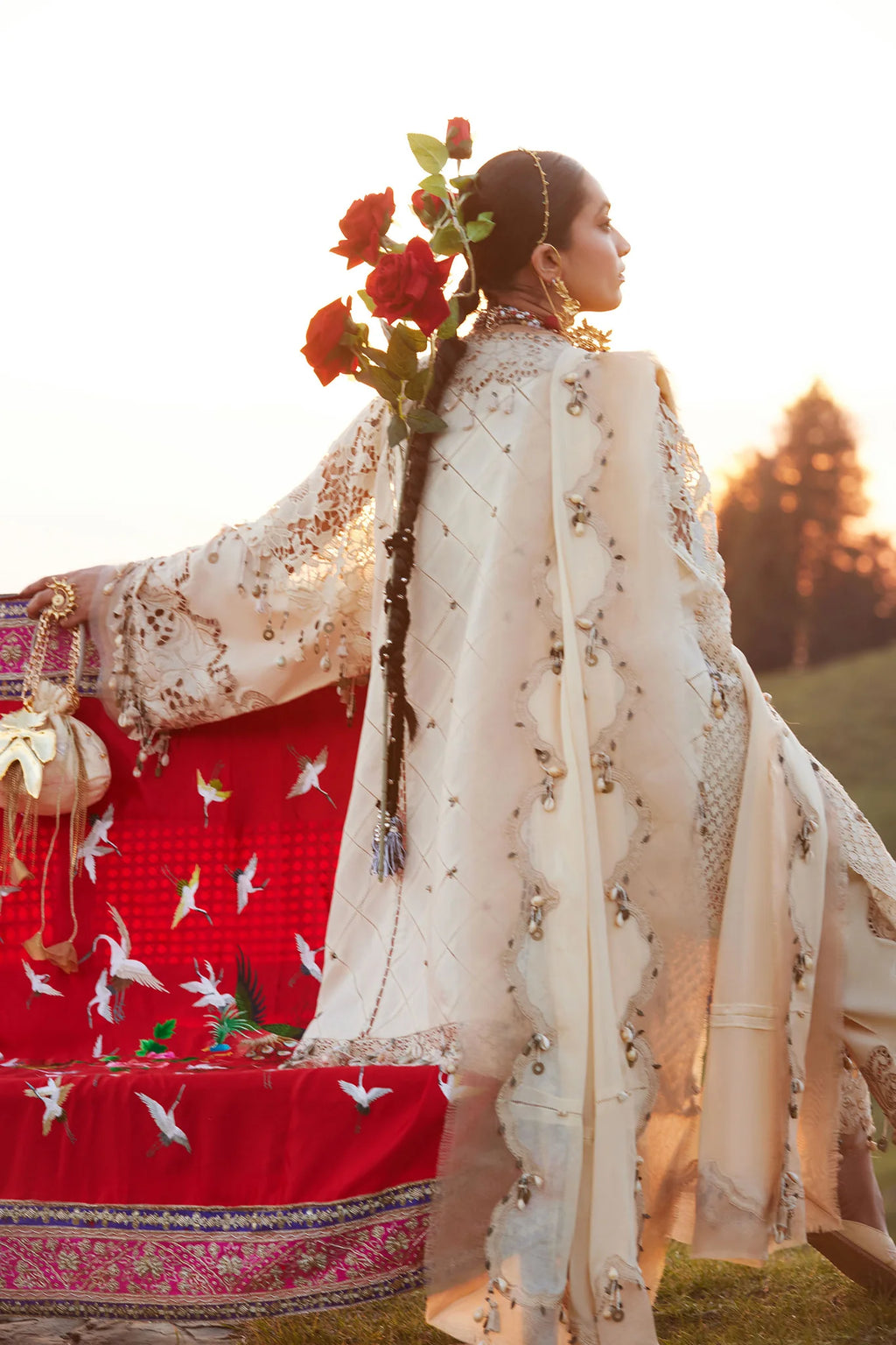 Woman in traditional attire with floral decorations against a sunset background