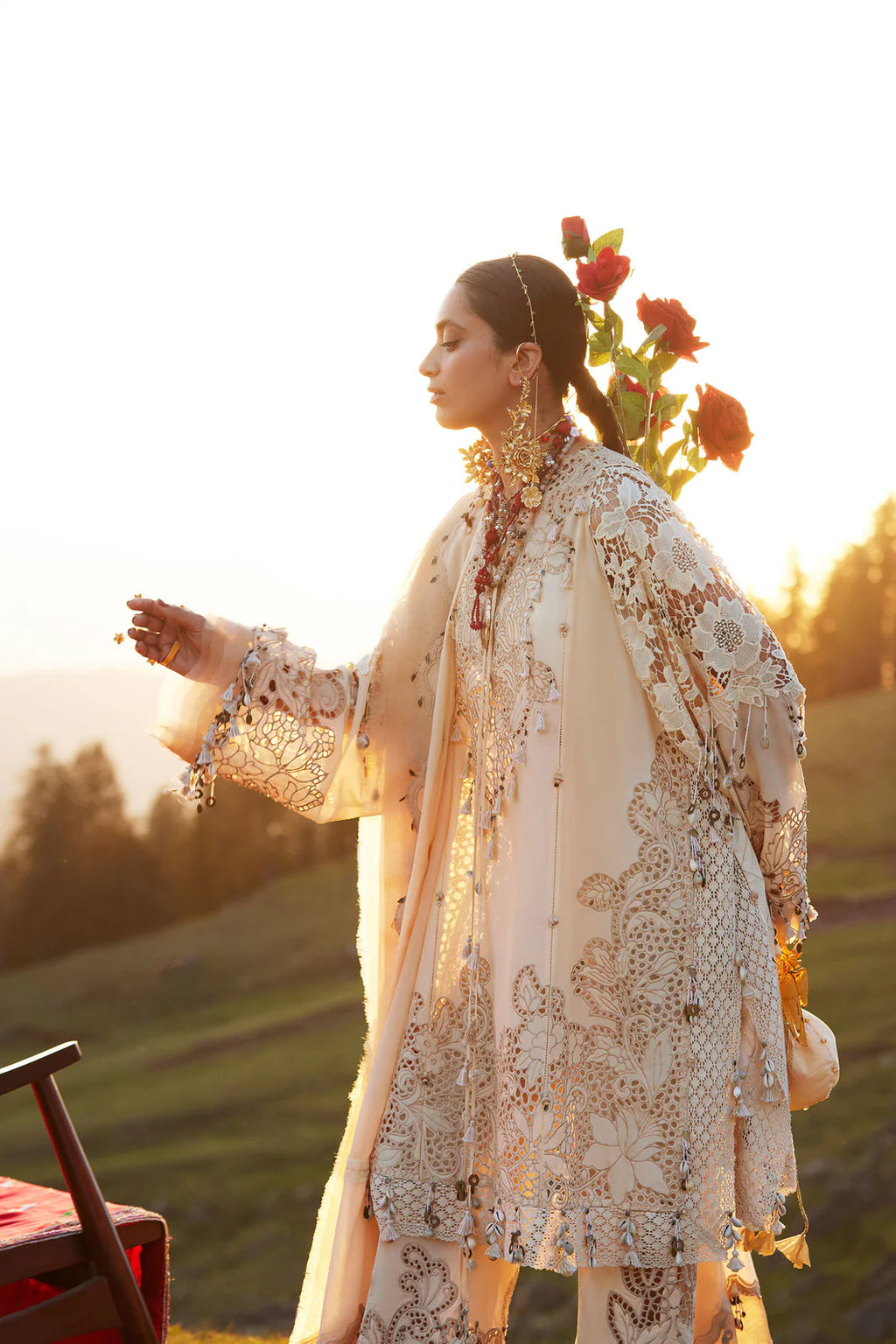 Woman in a traditional embroidered outfit standing outdoors with a scenic background