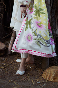 Person wearing a floral dress with a patterned scarf in a rustic setting
