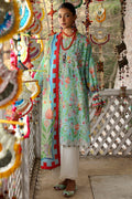 Woman in a colorful traditional outfit standing on a wooden deck with decorative hanging elements.