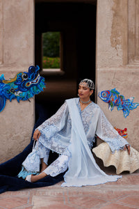 Woman in a traditional outfit sitting on a stone bench with decorative elements in the background.
