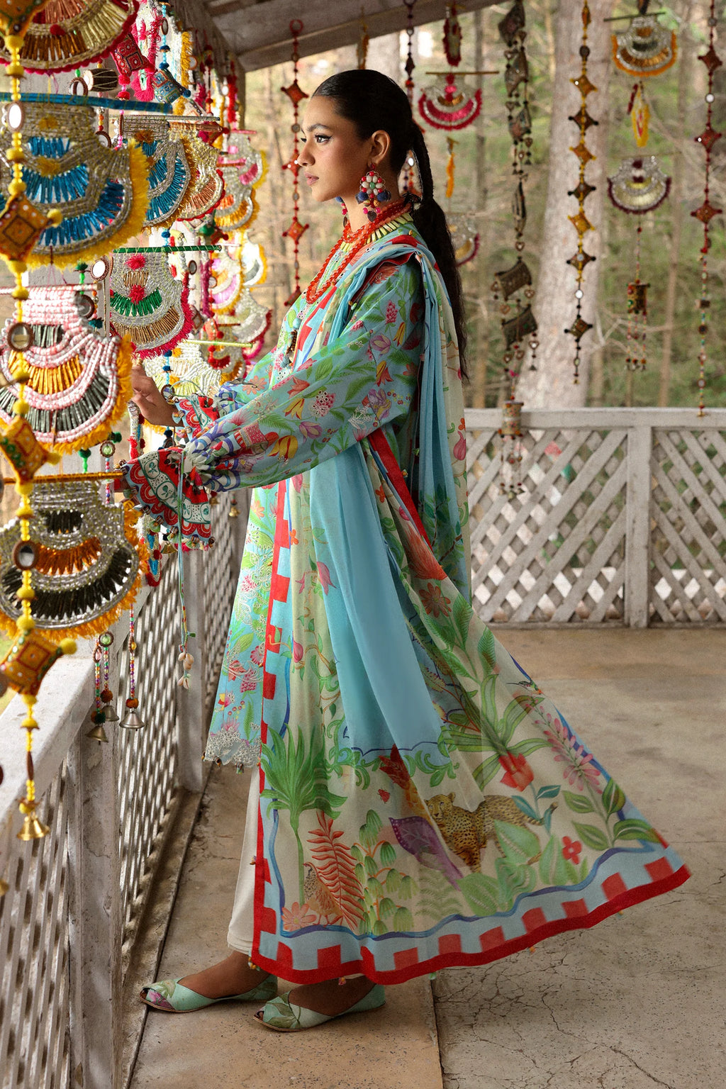 Woman in a colorful traditional outfit standing in a decorated indoor setting.
