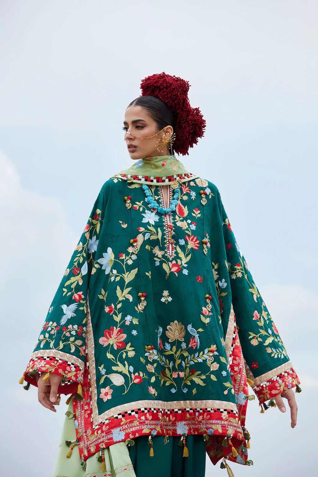 Woman wearing a green embroidered traditional outfit with a floral pattern against a light background