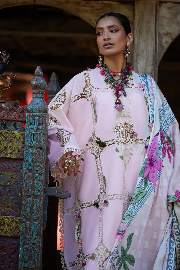 Woman in a traditional outfit with floral patterns and jewelry, standing in front of an ornate wooden door.